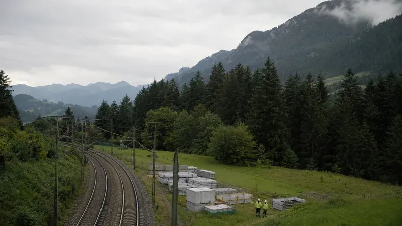 Bahntrasse im Alpenvorland mit Oberleitung und vorbereiteter Baustellenfläche