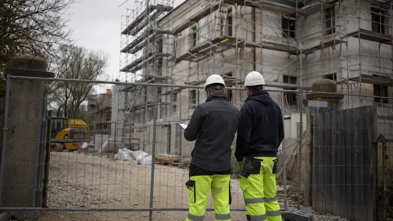 Handwerker am Baustelleneingang einer kommunalen Sanierung mit Gerüst