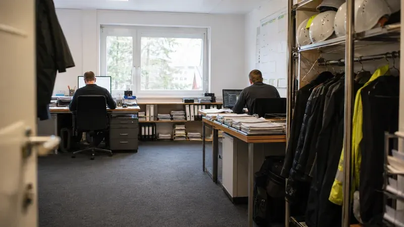 Kleines Handwerkerteam belädt Transporter am Rand einer großen Baustelle